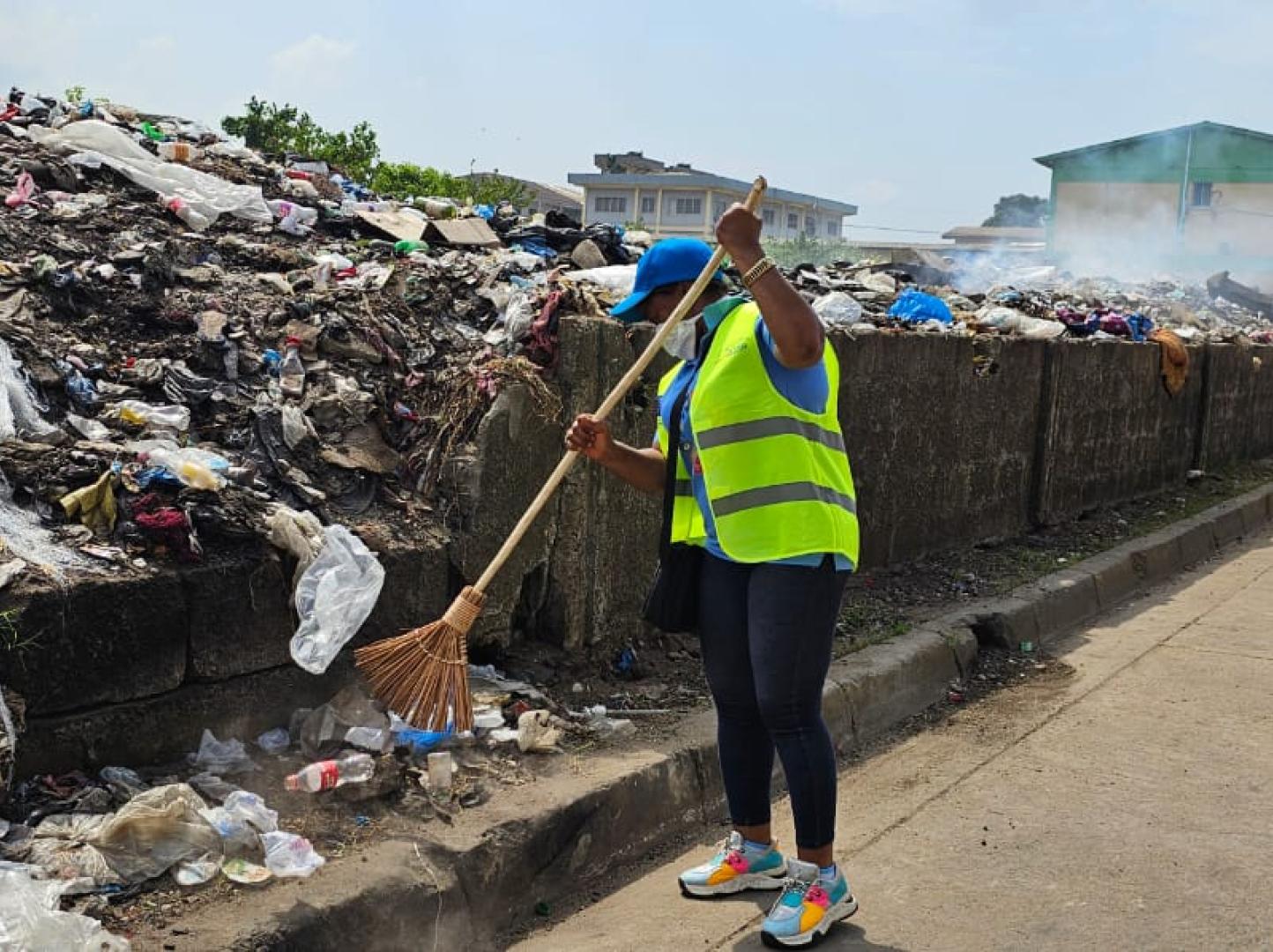 Women with broom sweeping near a pile of trash