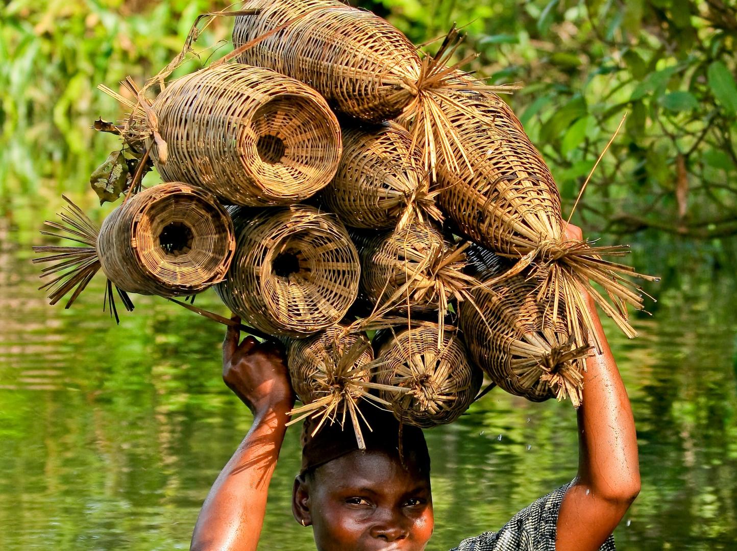 Woman in the river with fishing baskets on her head