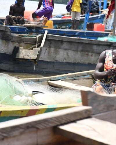 Young man seated in a canoe fixing a fishing net