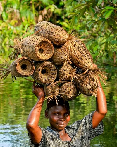 Woman in the river with fishing baskets on her head