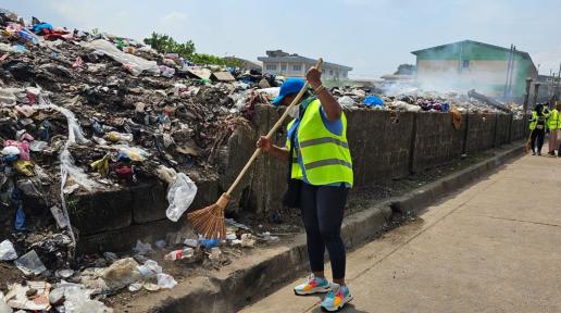 Women with broom sweeping near a pile of trash