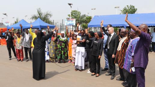 Photo of a people standing in a group with their arms raised